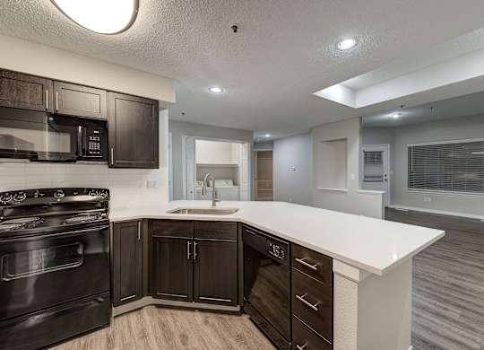 a kitchen with a white counter top and black appliances at Ashford Belmar Apartments, Lakewood