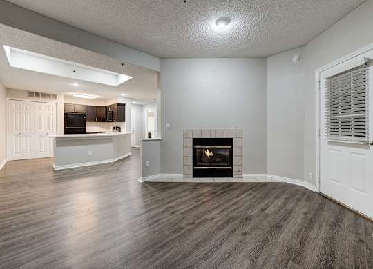 an empty living room with a fireplace and a kitchen at Ashford Belmar Apartments, Lakewood, Colorado