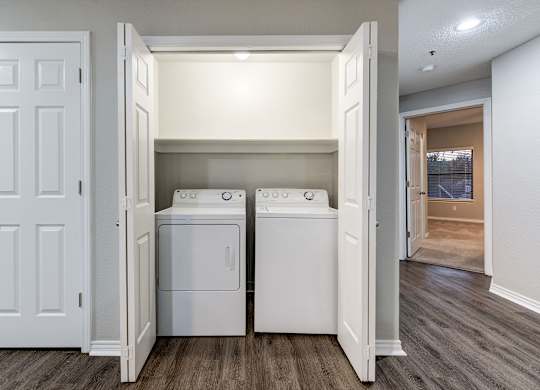 an empty laundry room with two washes and a dryer at Ashford Belmar Apartments, Lakewood, CO