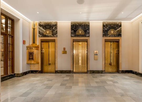 the lobby of a building with gold doors and a marble floor  at The Belden Stratford, Chicago