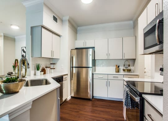 a kitchen with white cabinets and stainless steel appliances at Carrington at Barker Cypress, Cypress, TX