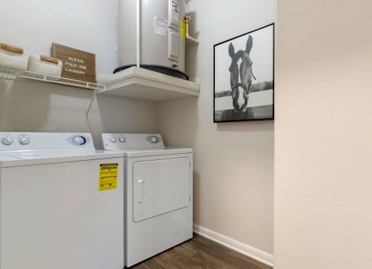 a laundry room with a washer and dryer and a painting on the wall at Madison on the Meadow, Stafford, Texas