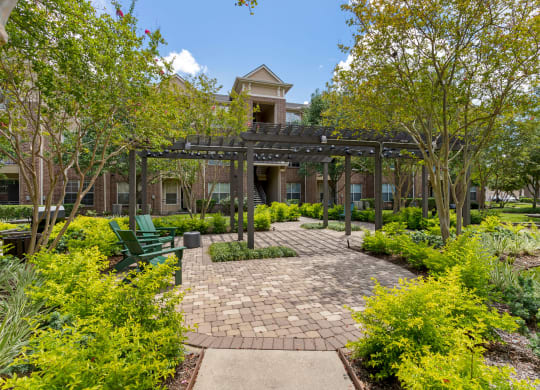 a courtyard with benches and a pergola in front of a building at Madison on the Meadow, Stafford, TX