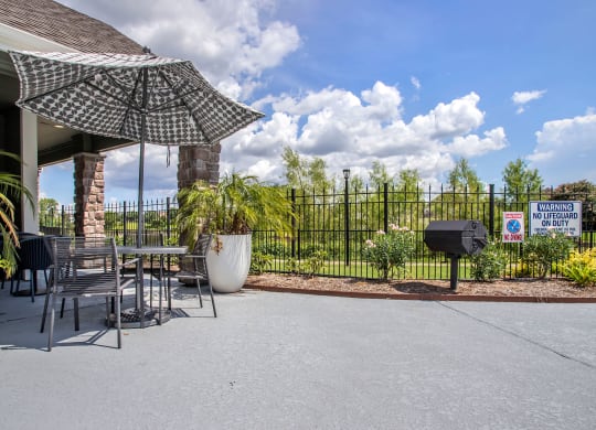 a patio with a table and chairs and an umbrella and a grill at Reserve by the Lake, Houston, TX, 77084