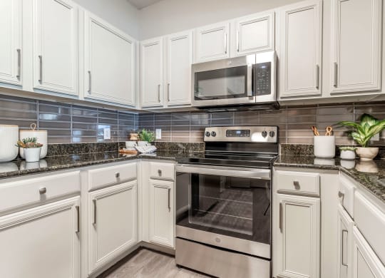 a kitchen with white cabinets and stainless steel appliances at Reserve by the Lake, Houston, Texas