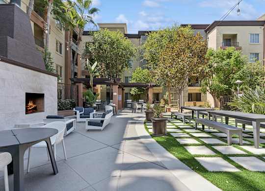 A patio with a fireplace and chairs. at The Kitt at Warner Center Apartments, Woodland Hills, CA, 91303