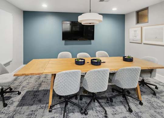 A conference room with a long table and chairs at The Kitt at Warner Center Apartments, Woodland Hills, CA, 91303