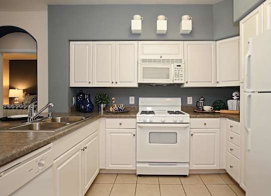 A kitchen with white appliances and cabinets at The Kitt at Warner Center Apartments, Woodland Hills 91303