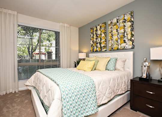 A bedroom with a large bed and a window with blinds. at The Kitt at Warner Center Apartments, Woodland Hills, California