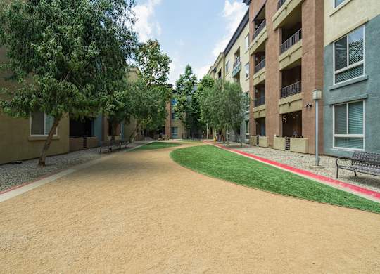 A long, narrow, dirt pathway leads between two rows of apartment buildings at The Kitt at Warner Center Apartments, Woodland Hills, California