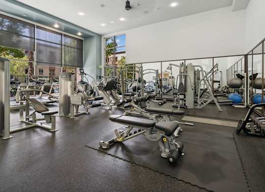 A gym with a variety of equipment including weights and machines. at The Kitt at Warner Center Apartments, California