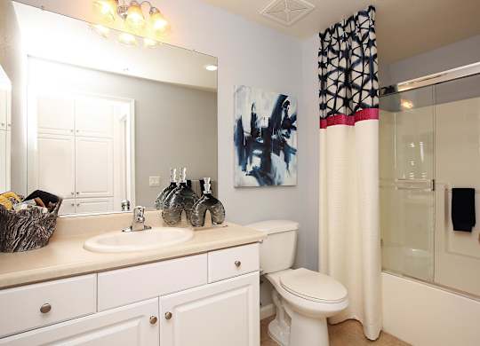 A bathroom with a white toilet, sink, and shower. at The Kitt at Warner Center Apartments, Woodland Hills, CA