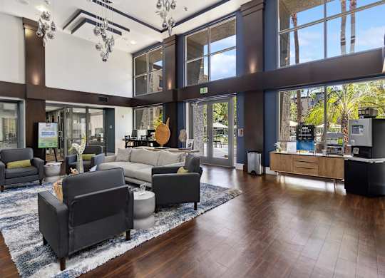 A large room with a lot of furniture and a view of trees outside the windows at The Kitt at Warner Center Apartments, Woodland Hills