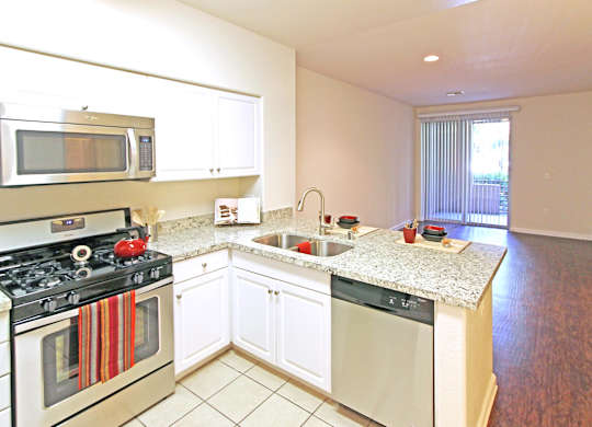 A kitchen with a stove, microwave, and oven at The Kitt at Warner Center Apartments, California