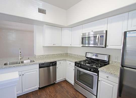A kitchen with white cabinets and stainless steel appliances at The Kitt at Warner Center Apartments, California, 91303