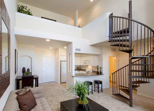A living room with a couch, a coffee table, and a staircase. at The Kitt at Warner Center Apartments, Woodland Hills, CA, 91303