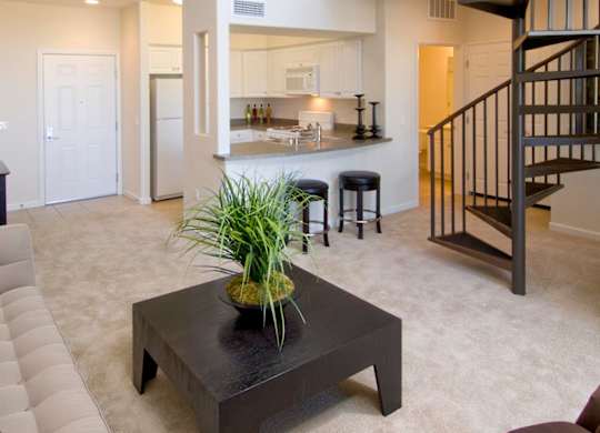 A living room with a spiral staircase and a coffee table at The Kitt at Warner Center Apartments, Woodland Hills 91303