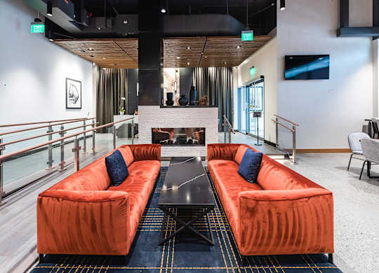 A room with orange couches and a fireplace.