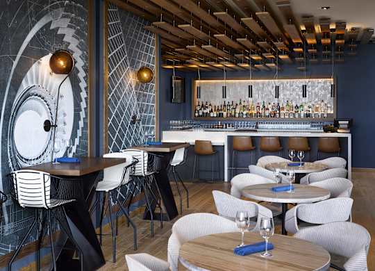 A restaurant with a bar and chairs.
