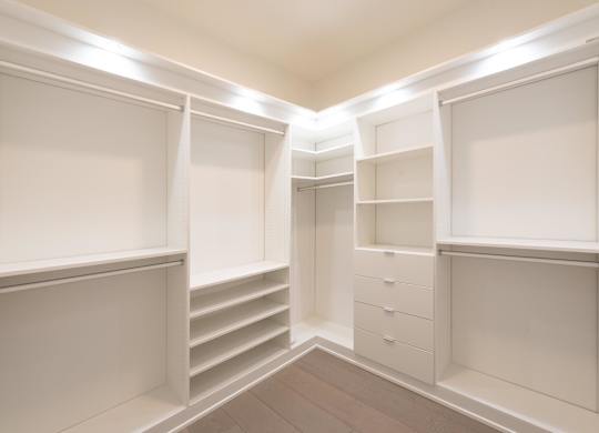 A walk-in closet with white shelves and drawers.