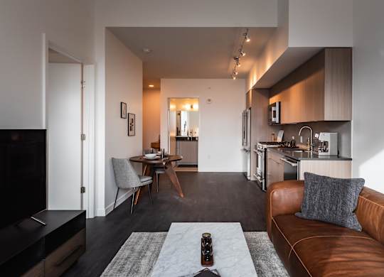 A modern living room with a brown leather couch and a grey rug.