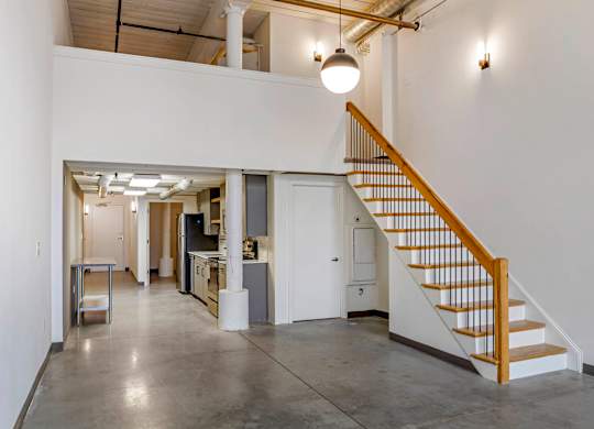 a room with a staircase and a white wall and a ceiling light at Highland Mill Lofts, Charlotte, NC