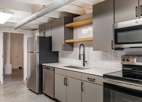 a kitchen with stainless steel appliances and white counter tops at Highland Mill Lofts, North Carolina