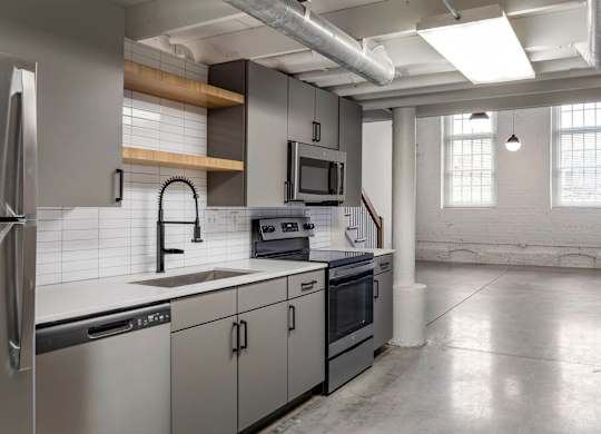 a kitchen with white counter tops and stainless steel appliances at Highland Mill Lofts, Charlotte, 28205