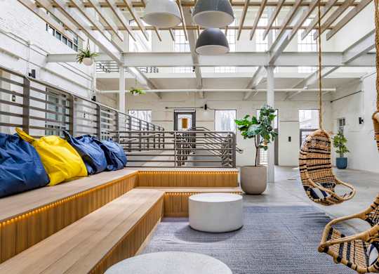 a living room with two hammock chairs and a wooden bench at Highland Mill Lofts, Charlotte, 28205