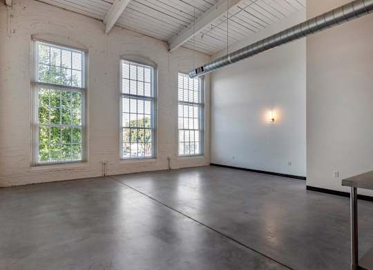 an empty room with three large windows and a table at Highland Mill Lofts, Charlotte, NC