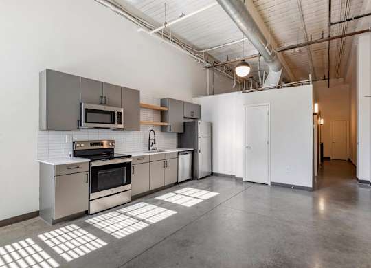 a kitchen with stainless steel appliances and white walls at Highland Mill Lofts, Charlotte