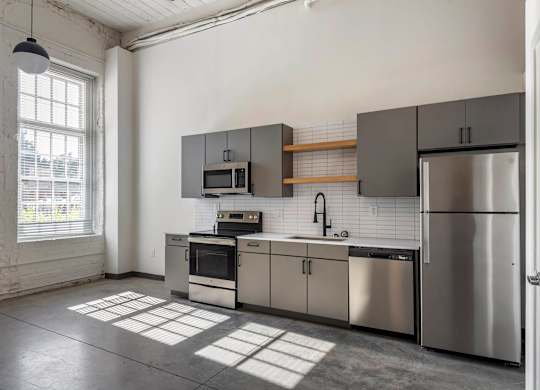 a kitchen with stainless steel appliances and a window at Highland Mill Lofts, Charlotte, North Carolina