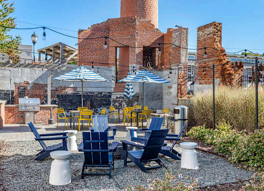 a patio with blue and yellow chairs and umbrellas at Highland Mill Lofts, Charlotte, North Carolina
