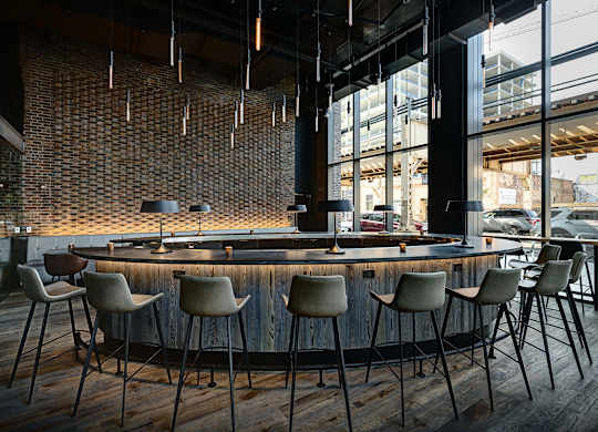 A bar with a brick wall and wooden chairs. at The Mason Apartments, Chicago