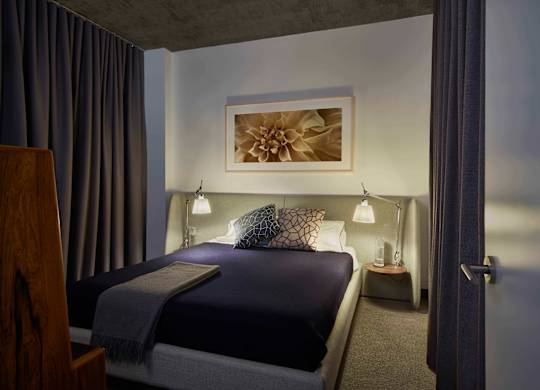 A bedroom with a bed, nightstand, and lamp. at The Mason Apartments, Chicago, Illinois
