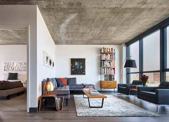 A modern living room with a concrete ceiling and a large window. at The Mason Apartments, Chicago, IL
