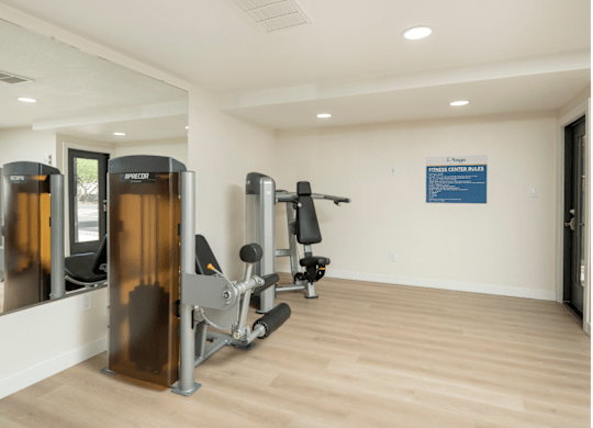 A gym with a row of treadmills and a sign on the wall.