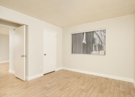 A room with a window and a wooden floor.