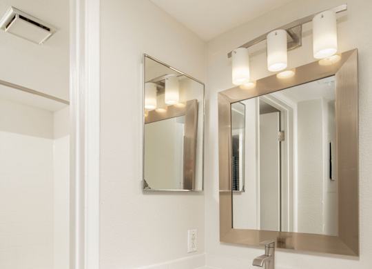 A white bathroom with a sink, mirror, and toilet.