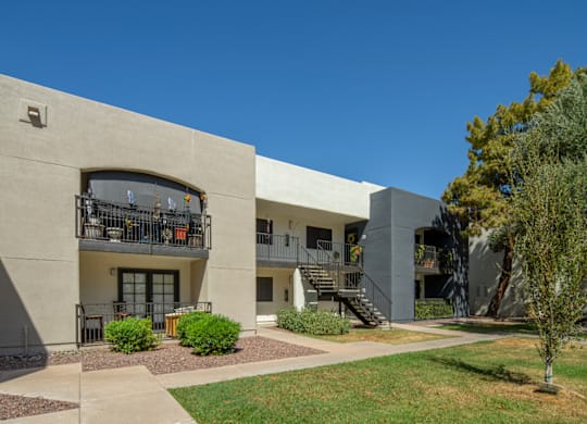 A building with a balcony and a tree in front.