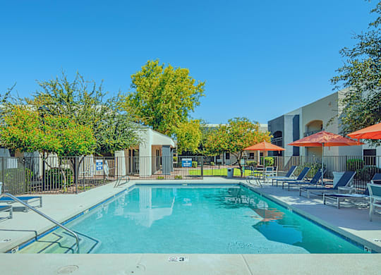 A swimming pool surrounded by trees and chairs.