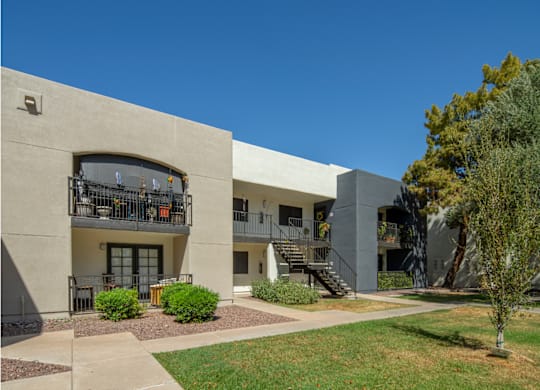 A concrete building with a balcony and stairs leading to the entrance.