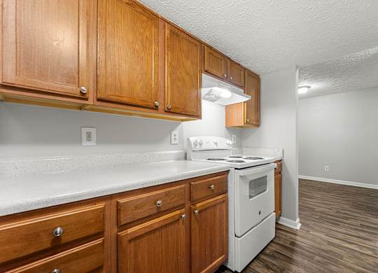 A kitchen with wooden cabinets and a white stove top oven.