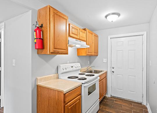 a kitchen with wood cabinets and white appliances at Gardens at Washington Park, Georgia , 30314