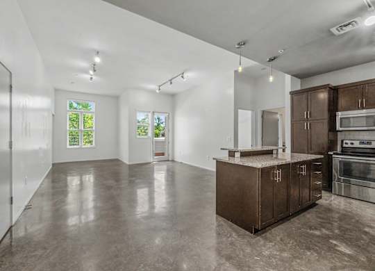 A spacious kitchen with brown cabinets and a concrete floor.