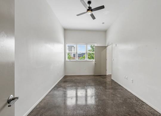 A room with a ceiling fan and a door leading to a balcony.
