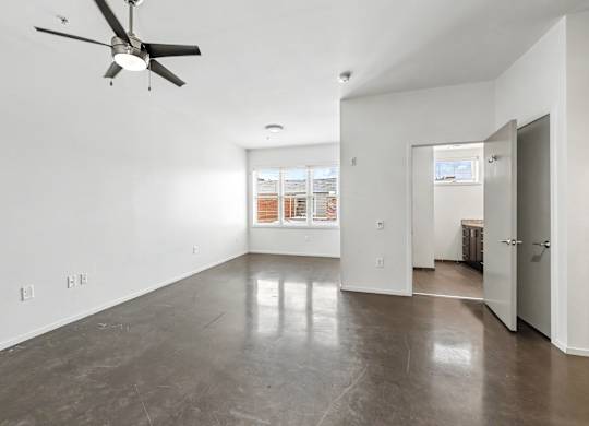 A room with a ceiling fan and a concrete floor.