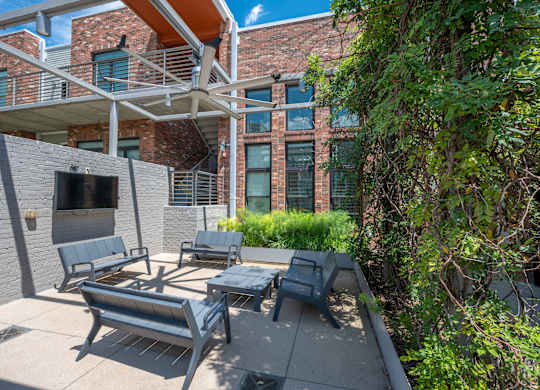 A patio with a table and chairs is in front of a brick building.