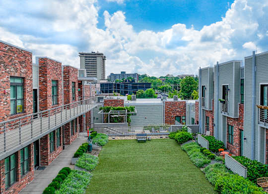 A courtyard surrounded by buildings with a blue sky and clouds in the background.