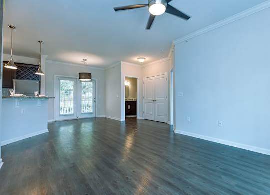 A spacious room with a ceiling fan and wooden flooring.